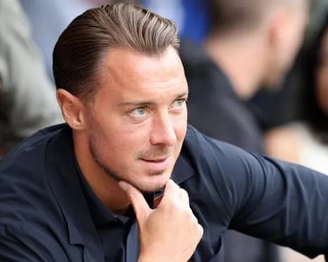 Newcastle manager Matthias Jaissle rests his chin on his hand, looking sideways