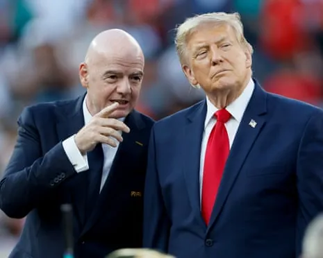 Gianni Infantino, wearing a black suit and black tie and white shirt, talks to Donald Trump, wearing a blue suit and white shirt and red tie