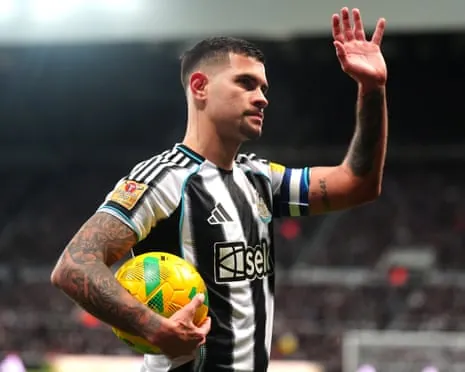 Bruno Guimarães holds a ball and waves to the crowd while playing for Newcastle